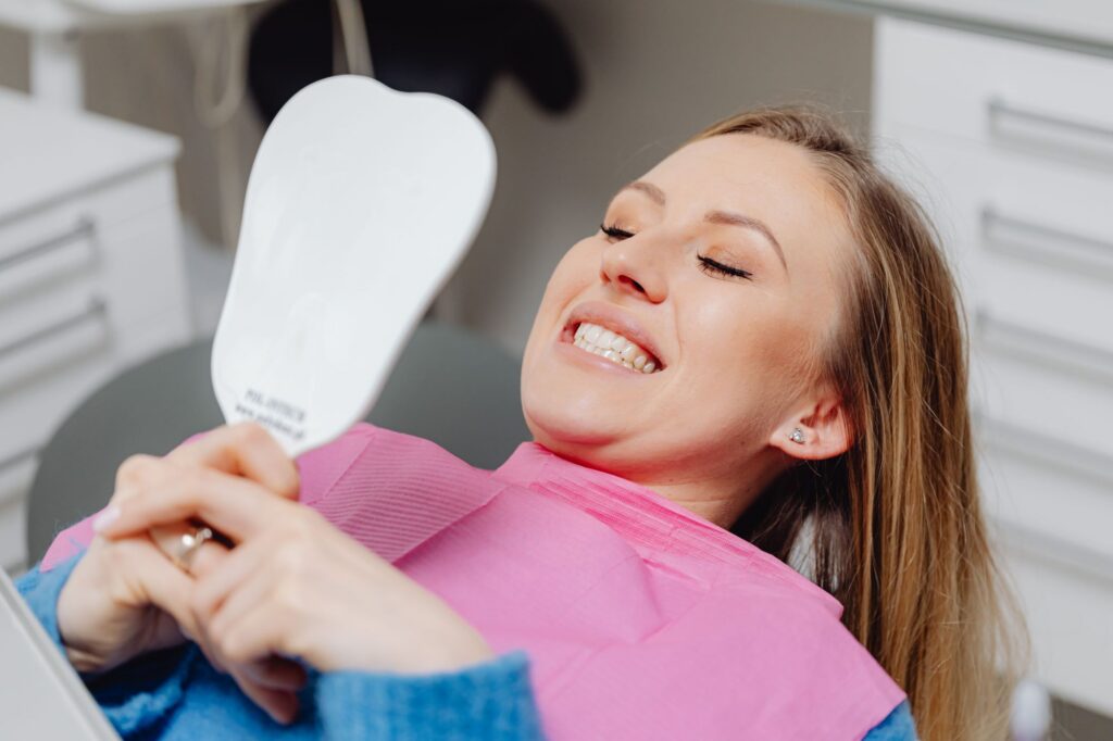 Smiling dental patient looking in a mirror after discussing cosmetic smile options